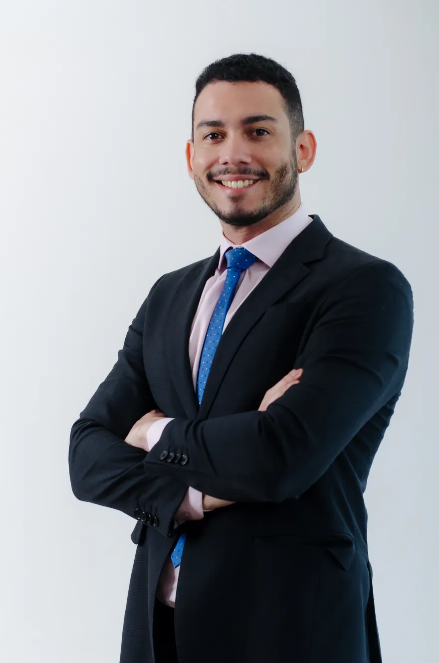 Ítalo Costa, de terno, braços cruzados e sorrindo